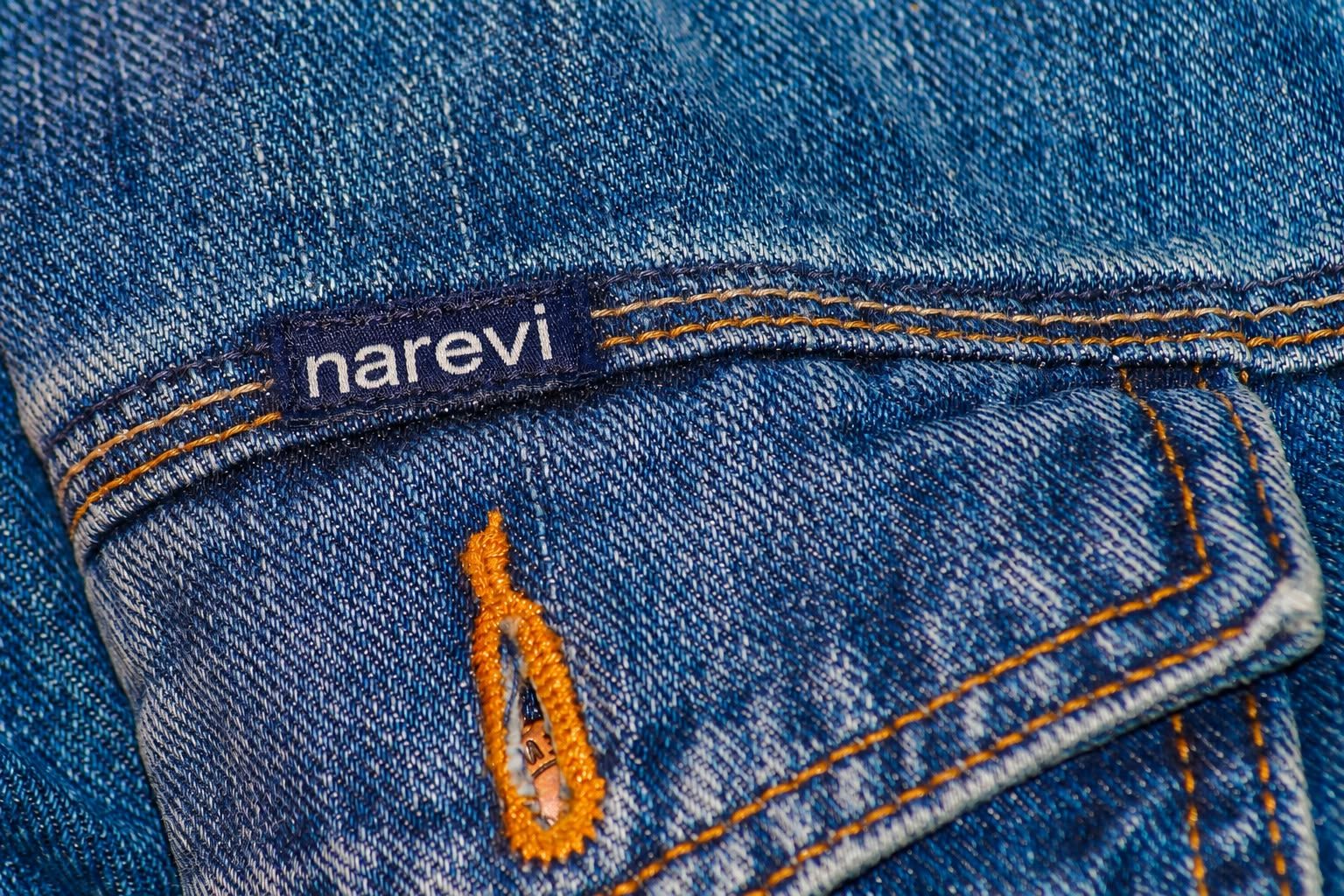 Textura do jeans com etiqueta NAREVI e costuras aparentes